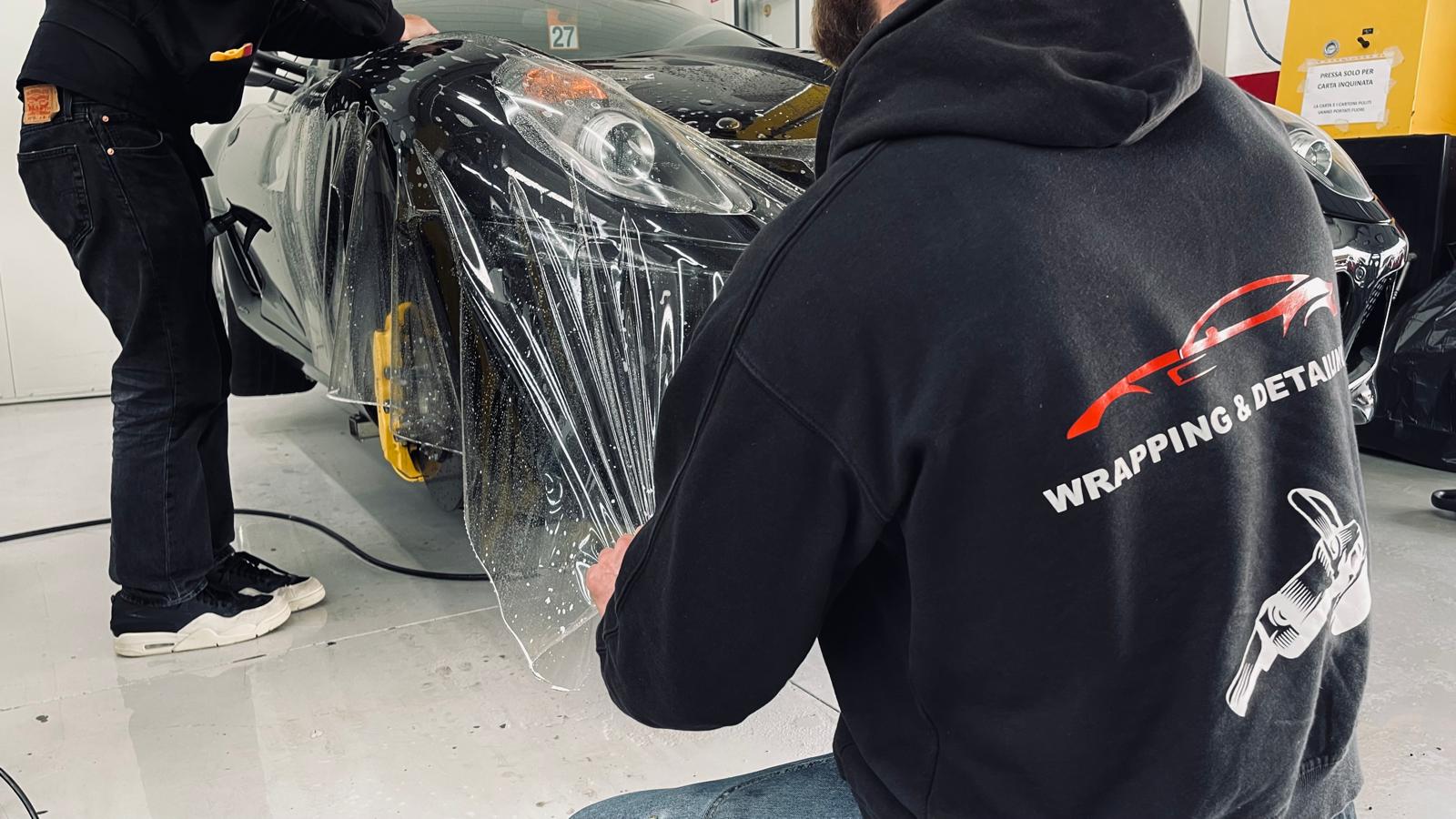 Un professionista di Detailing Studio 911 esegue l'installazione professionale di pellicola protettiva trasparente PPF (Paint Protection Film) sulla carrozzeria di un'auto di lusso a Parma.