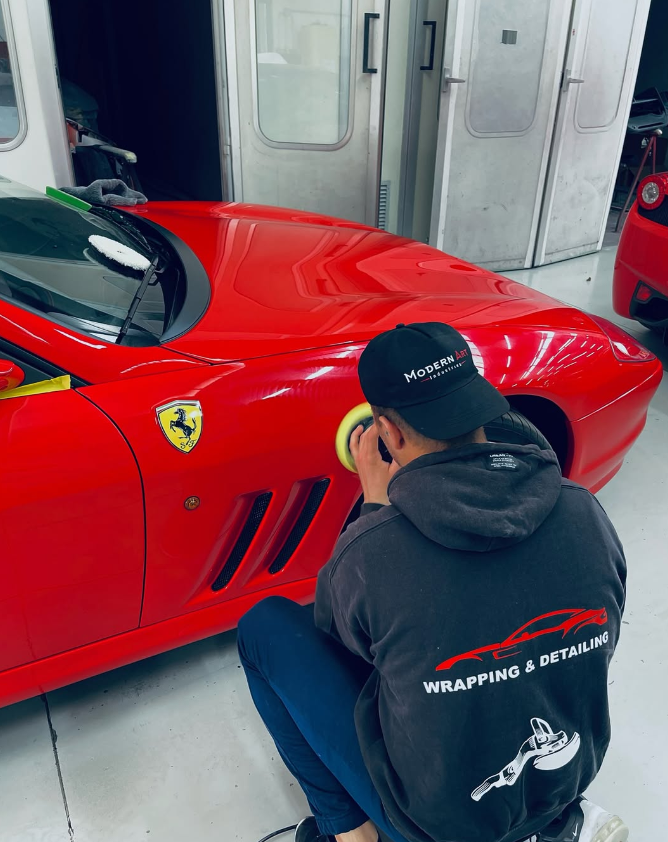 Un professionista di Detailing Studio 911 esegue la lucidatura professionale su una Ferrari rossa a Parma.
